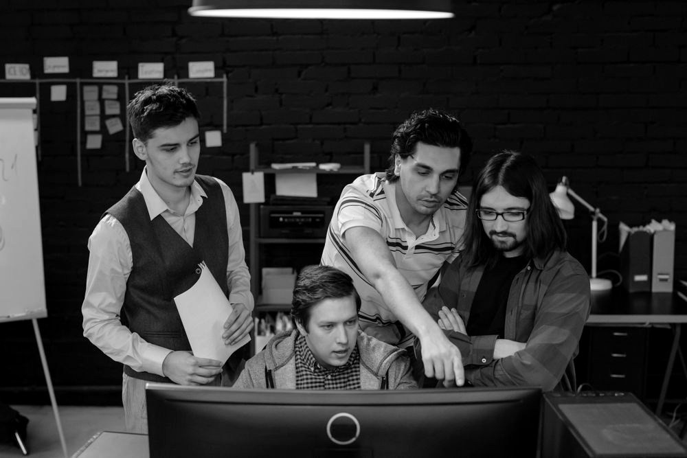 Four colleagues reviewing a computer screen together